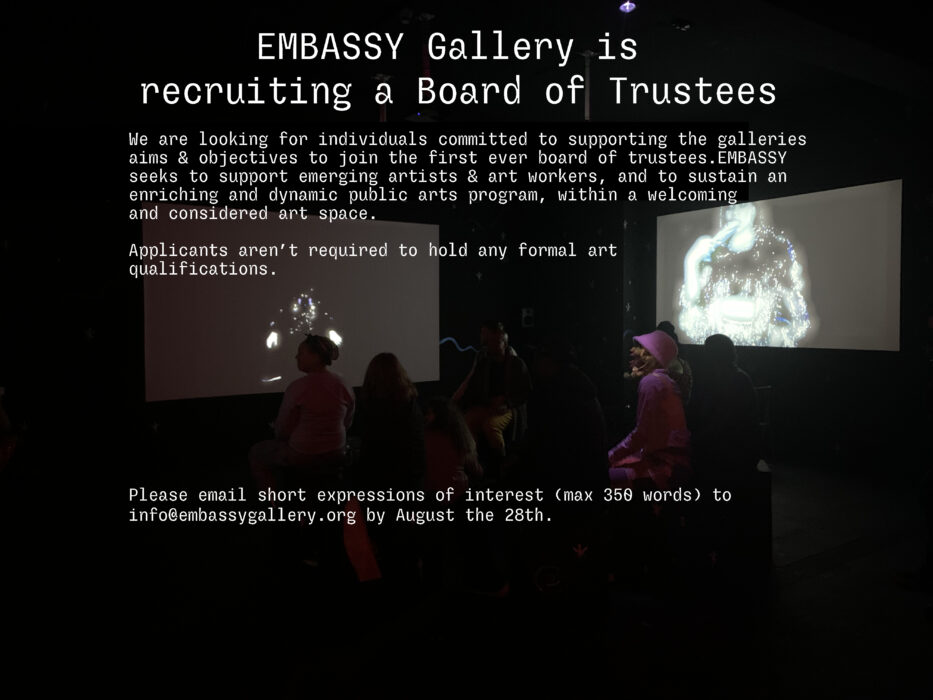 Text overlaying an image of a darkened gallery, with a group of people watching two projection screens
