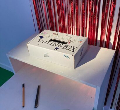 an image of a voting box, infront of a sparkly curtain