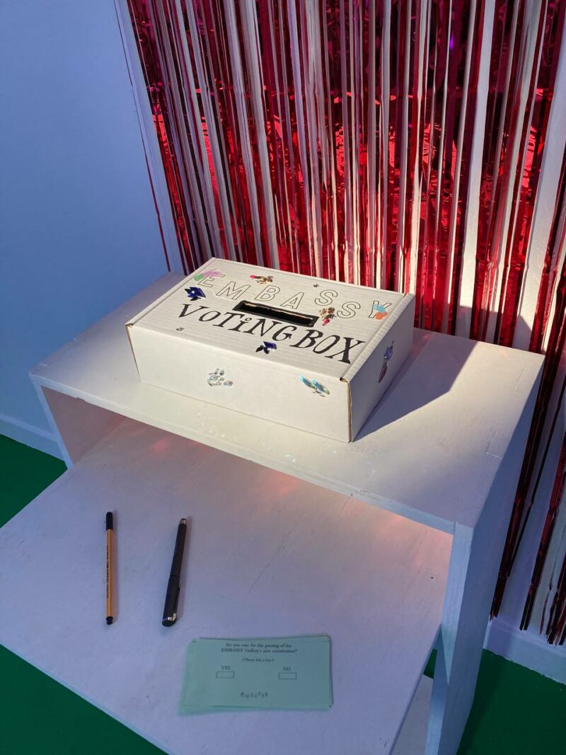 an image of a voting box, infront of a sparkly curtain